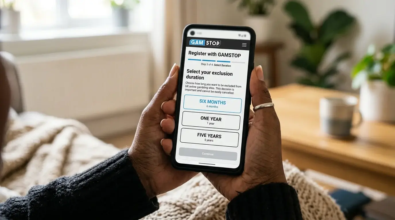 Mobile phone in a person's hand displaying the GAMSTOP registration form with the duration selection step visible